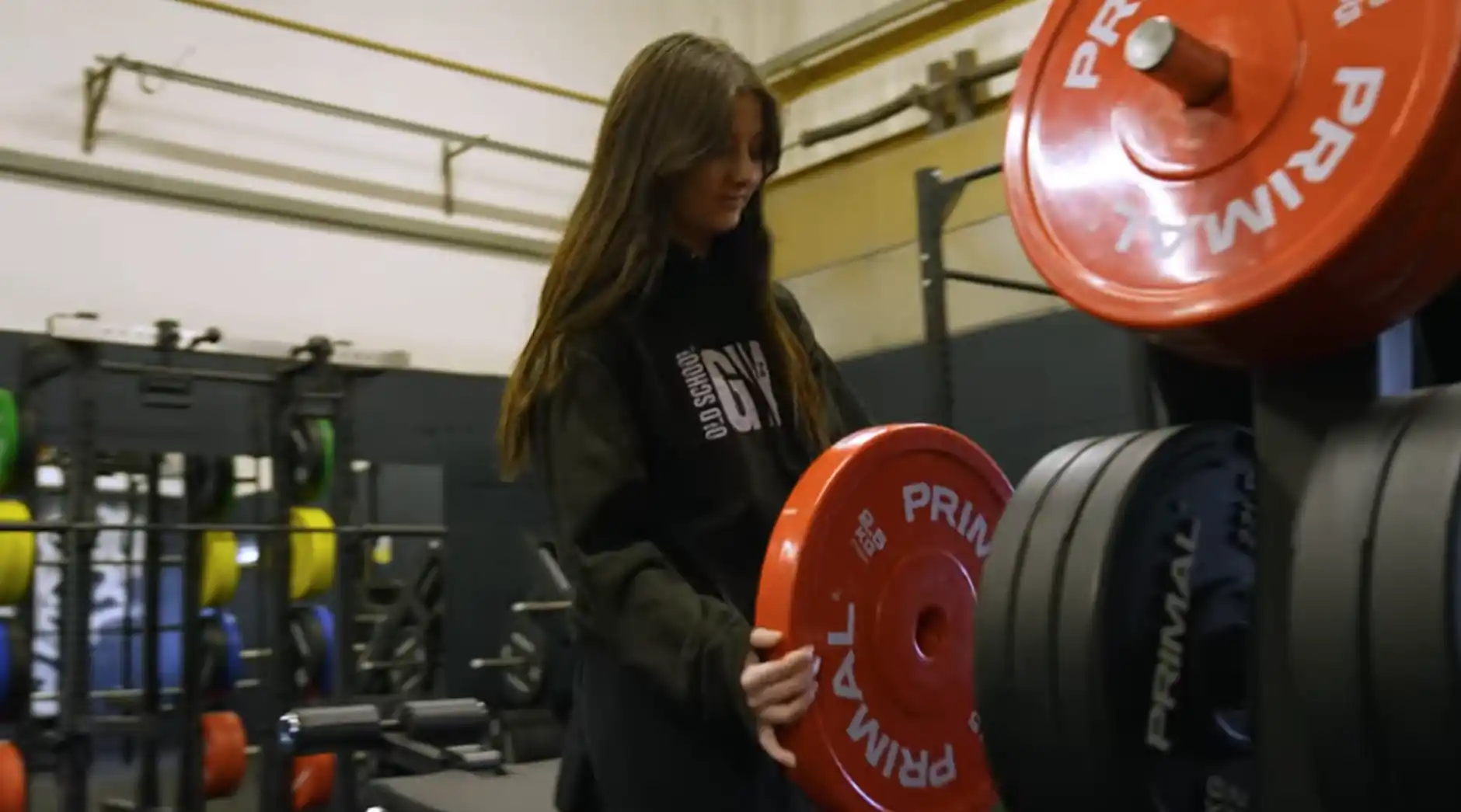 A women lifts a read weight onto equipment in a gym.