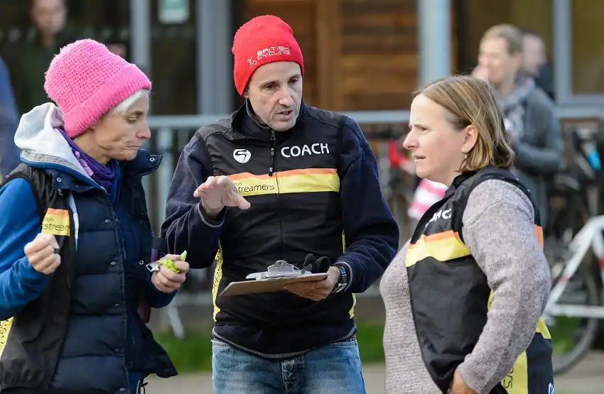 A group of coaches stand talking outside.