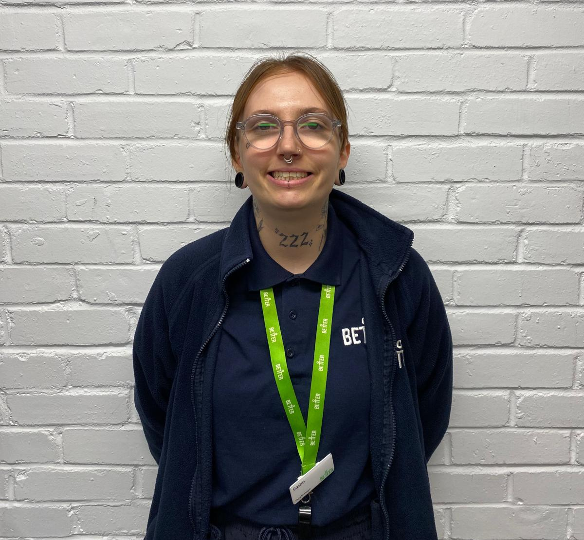 Sasha crop A lady with a GLL hoody and lanyard poses for a photos against a white brick wall