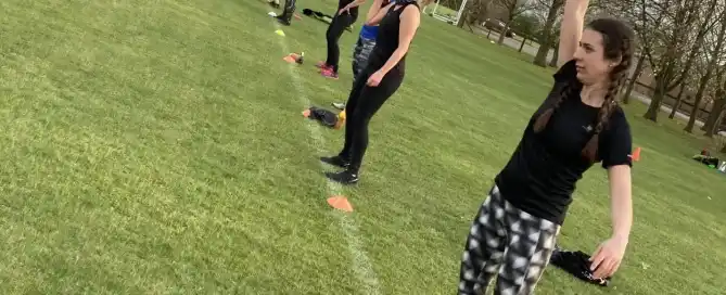 A line of women taking part in a bootcamp class in a field